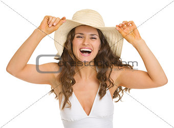 Portrait of smiling young woman in swimsuit and hat