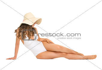Young woman in swimsuit and hat laying on floor