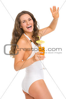 Happy young woman in swimsuit with cocktail saluting