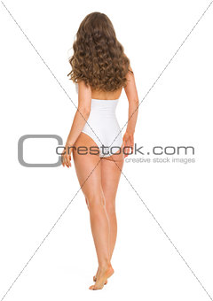Full length portrait of young woman in swimsuit going straight .