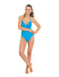 Full length portrait of smiling young woman in swimsuit