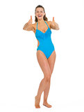 Full length portrait of happy young woman in swimsuit showing th