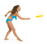 Happy young woman in swimsuit playing with frisbee