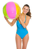 Smiling young woman in swimsuit with beach ball