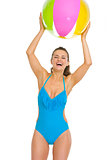 Happy young woman in swimsuit playing with beach ball
