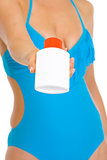 Closeup on sun block creme in hand of young woman in swimsuit