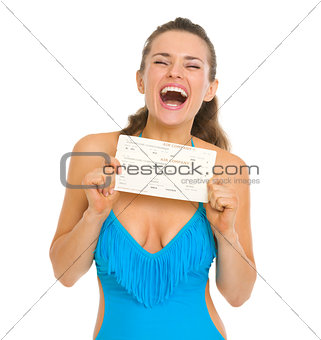 Excited young woman in swimsuit holding air tickets