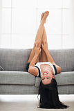 Smiling girl laying upside down on couch in living room