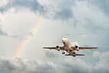 Airplane flying in sky with rainbow