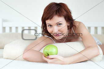 attractive young woman with an green apple at bed
