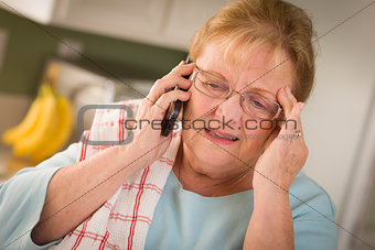 Shocked Senior Adult Woman on Cell Phone in Kitchen