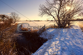  canal and wooden fence in snow at sunrise