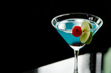 blue cocktail with cherry and lime
