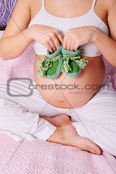 beautiful young pregnant  woman at home holding a daisy