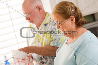Senior Adult Couple Washing Dishes Together Inside Kitchen