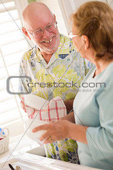 Senior Adult Couple Washing Dishes Together Inside Kitchen