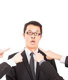 all hands pointing towards surprised businessman