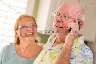 Senior Adult Husband on Cell Phone with Wife Behind