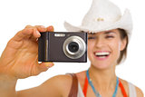 Closeup on camera in hand of young beach woman in hat