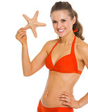 Smiling young woman in swimsuit showing starfish