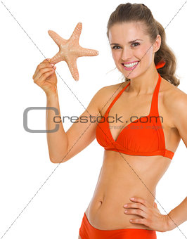 Smiling young woman in swimsuit showing starfish