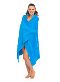 Happy young woman in swimsuit bundle up in towel