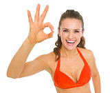 Happy young woman in swimsuit showing ok gesture