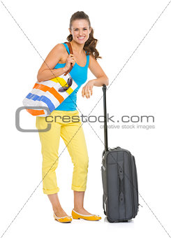 Smiling young tourist woman with wheel bag