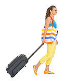 Young tourist woman with wheel bag going sideways