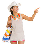 Happy young beach woman in hat pointing on copy space