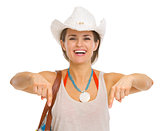 Smiling young beach woman in hat pointing down on copy space