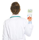 Medical doctor woman holding pack of euros . rear view