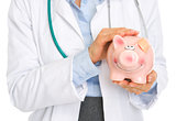 Closeup on medical doctor woman holding piggy bank with patch on