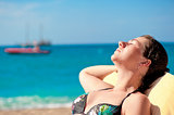 Portrait of sunbathing girl on a background of the sea and the schooner.