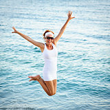 happy young woman is jumping in the beach 