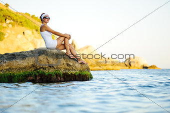 woman sitting on a stone in the sea