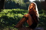 young sexy woman sitting on log posing