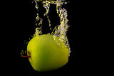 Green apple in yellow splash isolated on black background