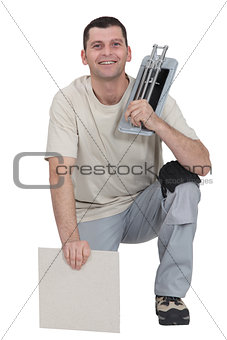 Man kneeling with tile cutter
