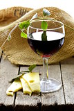 glass of red wine and slices of cheese on a wooden table