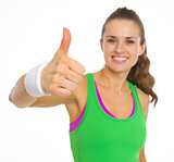 Closeup on fitness young woman showing thumbs up