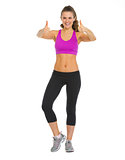 Full length portrait of happy fitness young woman showing thumbs