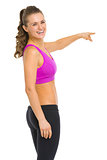 Smiling fitness young woman pointing on copy space