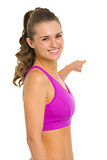 Portrait of smiling fitness young woman pointing back on copy sp