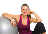 Happy fitness young woman sitting with fitness ball