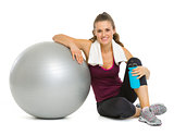 Happy fitness young woman sitting near fitness ball after workou