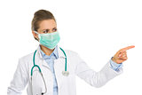 Medical doctor woman in mask pointing on copy space