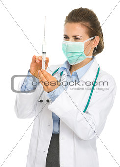 Medical doctor woman in mask with syringe preparing injection