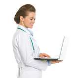 Smiling medical doctor woman working on laptop