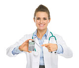 Smiling medical doctor woman pointing calculator